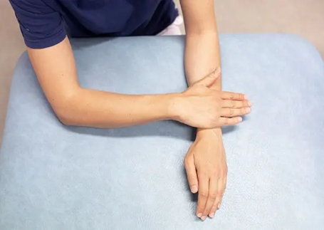 Foto af arm, der ligger p&aring; et underlag med den anden h&aring;nds h&aring;ndflade ovenp&aring;. Form&aring;let er at illustrere &oslash;velsen, der ogs&aring; er beskrevet med ord.