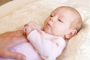Photo of an adult hand on a baby's stomach