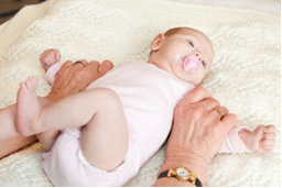 Photo of an adult holding a baby's  upper arms with a firm grip