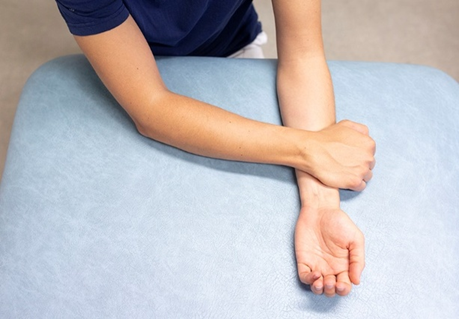 Foto af arm, der hviler p&aring; et underlag, samtidig med at den anden arms h&aring;nd ligger ovenp&aring; underarmen. Form&aring;let er at illustrere &oslash;velsen, der ogs&aring; er beskrevet med ord.